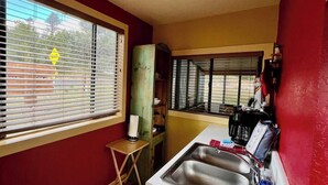A compact kitchen with a sink, a small table, and a window with blinds. - Cozy cabin at Inn at Lake Roberts (Lake Roberts)