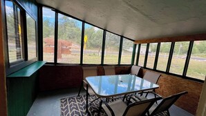 A room with a glass table and chairs, large windows, and a view of the outdoors. - Cozy cabin at Inn at Lake Roberts (Lake Roberts)