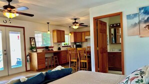 Una habitación pequeña y luminosa con cama, kitchenette y comedor.