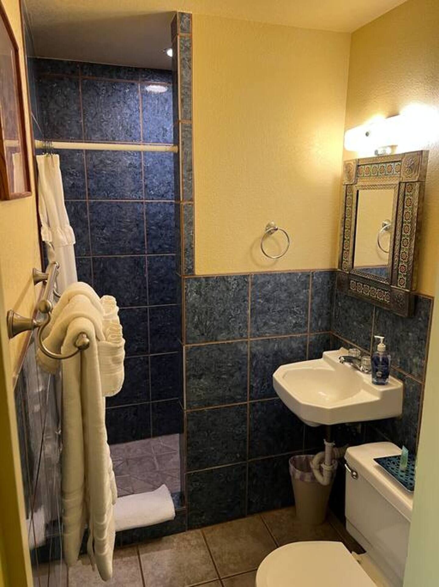 Un baño con ducha, lavamanos, inodoro y toallero.