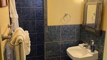 Un baño con ducha, lavamanos, inodoro y toallero.