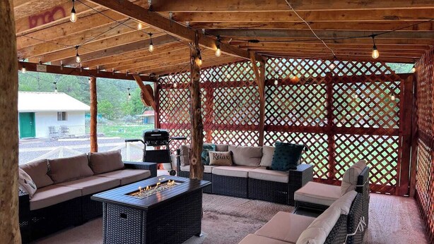 Un patio al aire libre con mobiliario de mimbre, un brasero y un techo de madera.