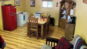Un espacio habitable compacto con comedor, cocina y televisor montado en la pared.