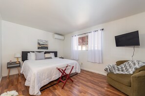 A bedroom with a bed, a TV, a window with curtains, a chair, and a painting on the wall. - A/C, Pet Friendly/ 3BR + Rec Room in Blue Lake Springs (Arnold)
