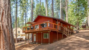 Eine Holzhütte mit einer Holzterrasse und einer Treppe zu einem zweiten Stockwerk.