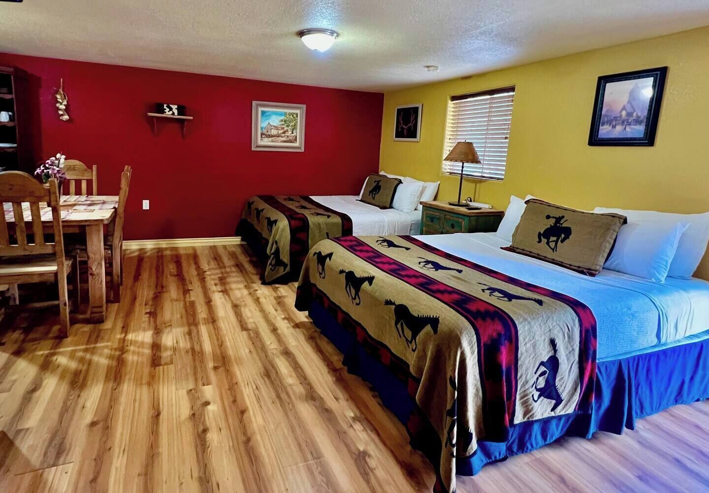 Una habitación con dos camas, una mesa de madera y sillas.