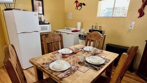 A dining area with a wooden table set for four, surrounded by wooden chairs. A white refrigerator and microwave are visible in the background. - Lovely Pet-Friendly Suite with Kitchen at Lake Roberts (Lake Roberts)