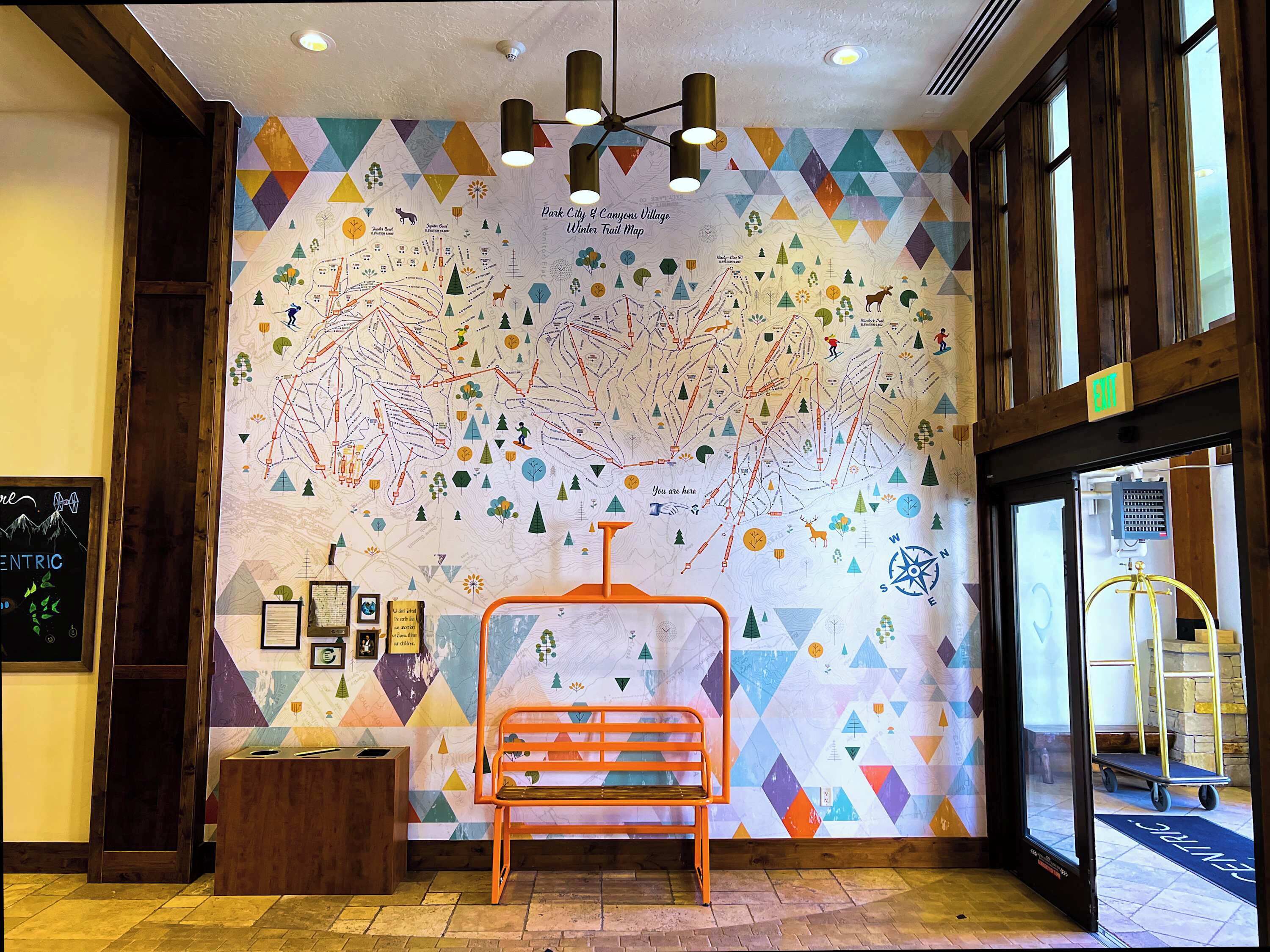 A lobby with a colorful map mural, a wooden bench, and a reception desk.