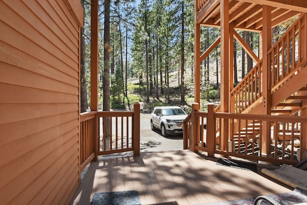 Staircase leads to a covered outdoor deck with a rug.