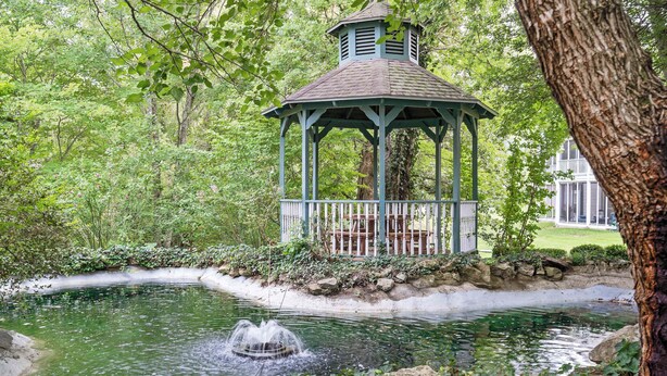 Ein Pavillon mit Teich und Brunnen in einem üppigen Garten.