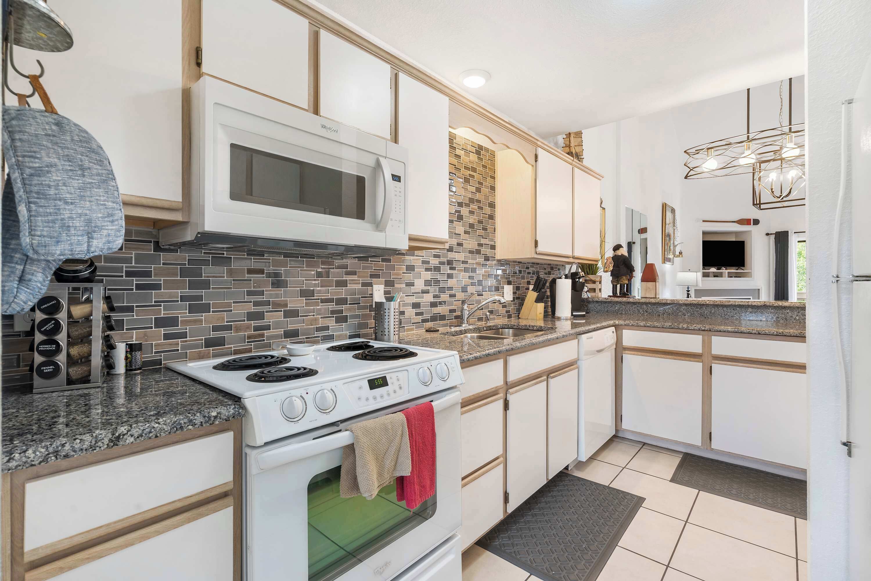 A modern kitchen with white cabinets, a granite countertop, a built-in microwave, and a stove.