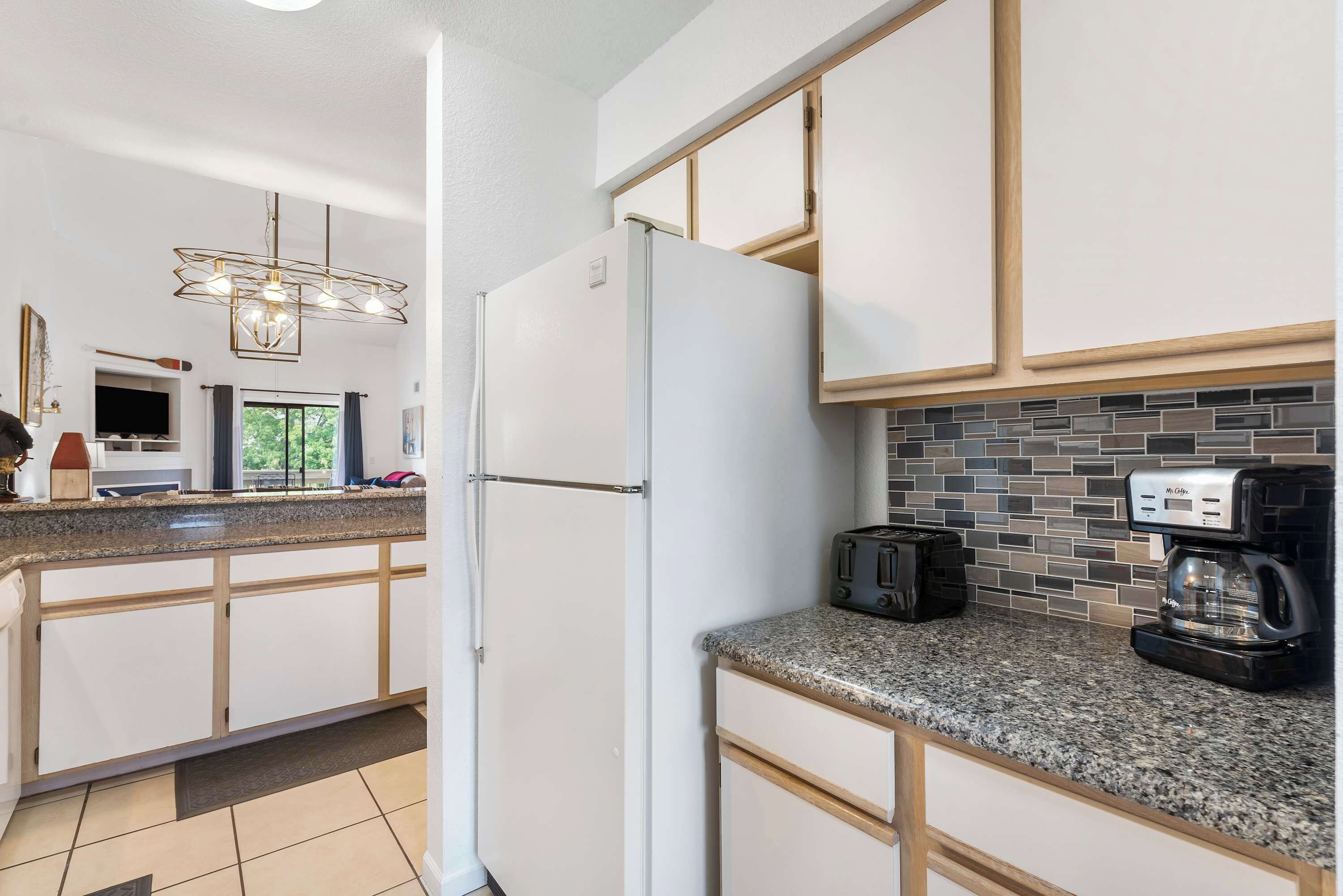 Eine moderne Küche mit weißen Schränken, Granit Arbeitsplatten, einem integrierten Kühlschrank, einer Kaffeemaschine und einem Toaster.
