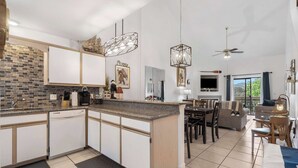 A modern kitchen with a central island, white cabinetry, and a tiled backsplash. - Nantucket at the Pointe - Adventure & Relaxation! (Branson)