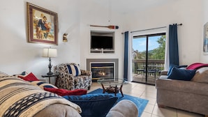 A living room with a fireplace, a television, and a balcony with a view. - Nantucket at the Pointe - Adventure & Relaxation! (Branson)
