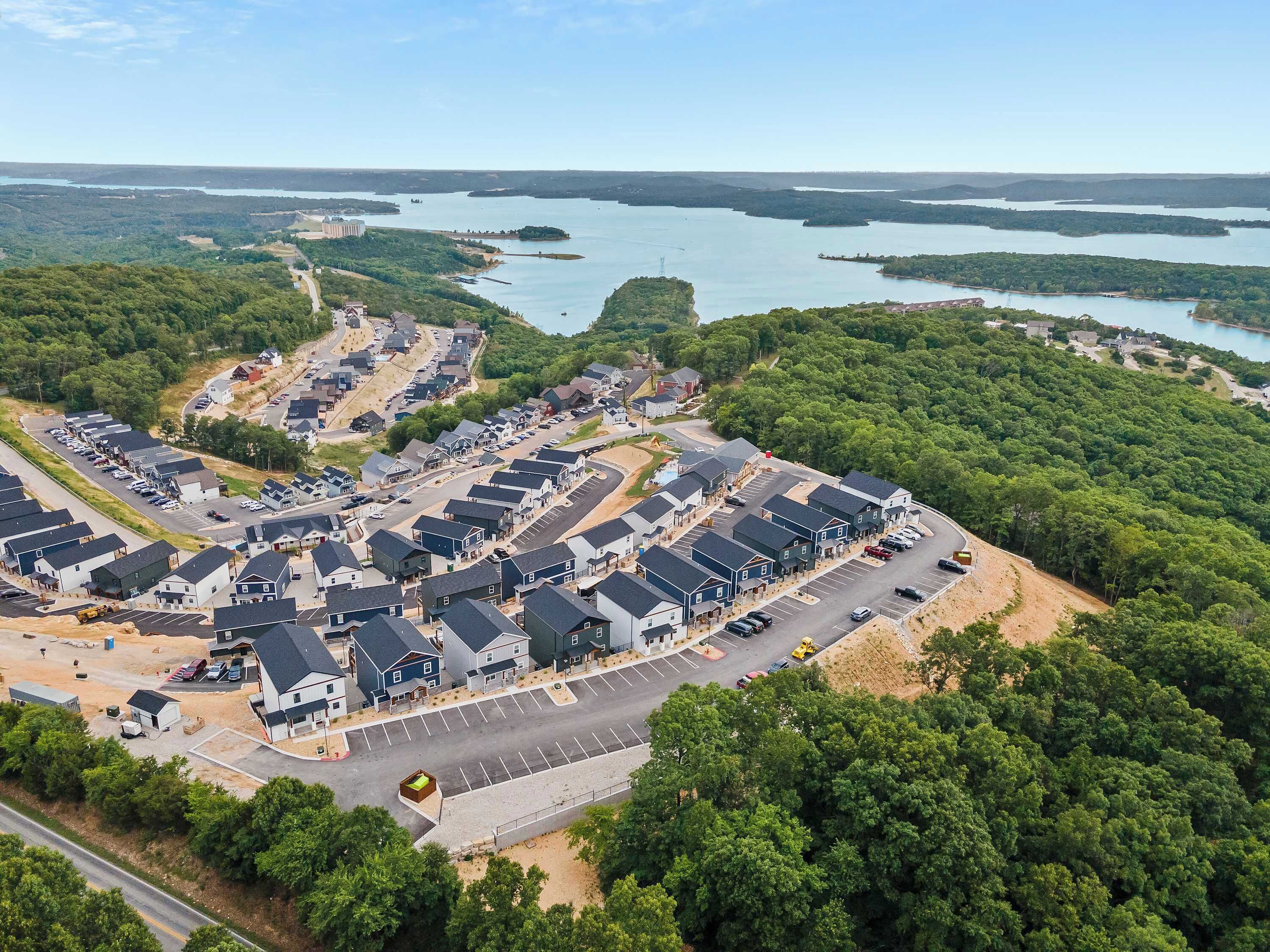 Vista aérea de una zona residencial con casas, carreteras y una gran masa de agua al fondo.