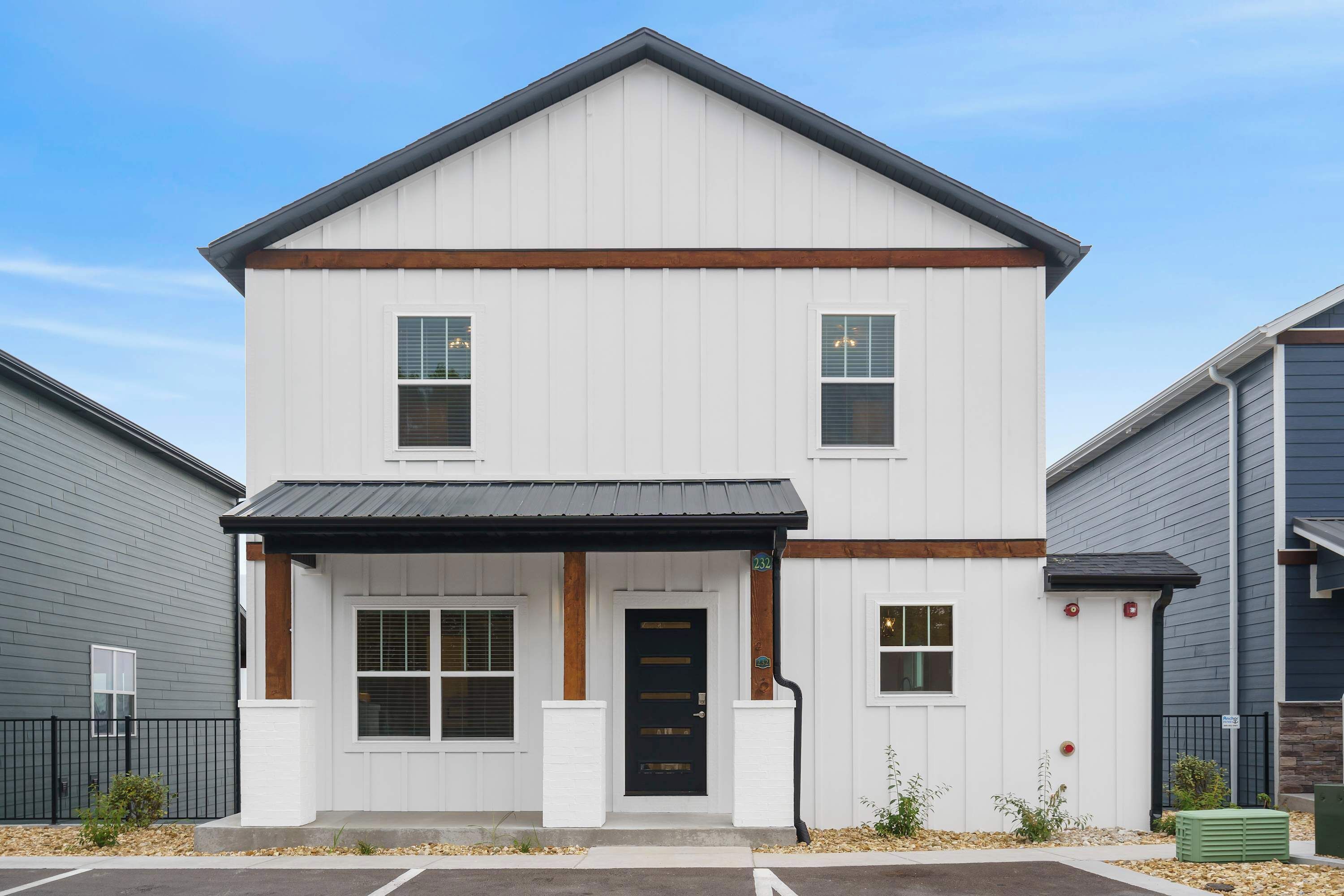 A two-story building with a black front door, white siding, and a small porch area.