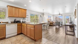 A spacious kitchen with wooden cabinets, a dishwasher, and a dining area with a table and chairs. - Retreat at Par Lane - Family Friendly Condo (Branson West)