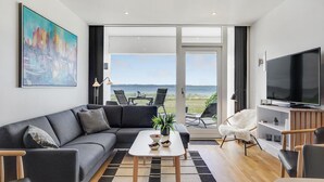 A modern living room with a grey sofa, a coffee table, a TV, and a view of the outdoors.