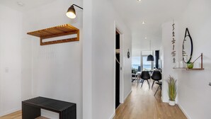 A modern interior with a wooden bench, a dining area with chairs, and a view of the sea through a large window.