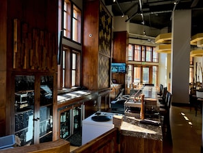 Enjoy dining in our restaurant with a long counter, various seating options, and large windows offering views of the outdoors.