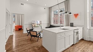 A modern kitchen with a central island, white cabinetry, and a view of the city. - Luxury 1BD Rittenhouse Sq. | Hosted By Stay Rafa (Philadelphia)