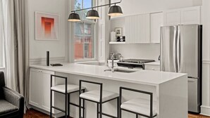A modern kitchen with white cabinetry, a central island with bar stools, a stainless steel refrigerator, and pendant lighting. - Luxury 1BD Rittenhouse Sq. | Hosted By Stay Rafa (Philadelphia)