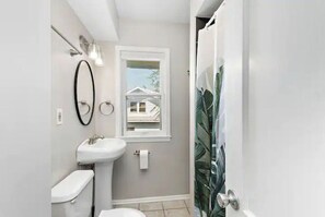 Bathroom with a modern design, featuring a white sink and toilet, and a window with a view.
