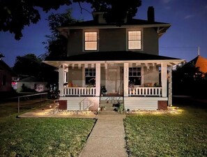Stunning two-story home with a central entrance and covered porch, set amidst a beautifully manicured lawn.