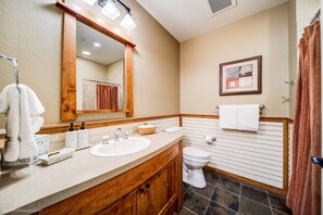 A bathroom with a wooden vanity, a sink, a mirror, a toilet, and a shower curtain. - Silver Mtn Studio Condo Ski - Mtn Bike- Hiking (Kellogg)