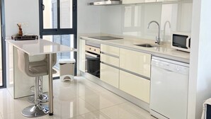 Eine moderne Küche mit einer zentralen Kochinsel, Edelstahlgeräten und einem Geschirrspüler.