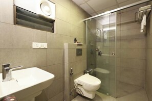 A modern bathroom with a white sink, a toilet, and a glass-enclosed shower area. - Ginger Ahmedabad Rto Circle (Ahmedabad)