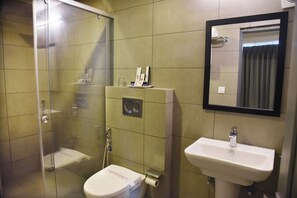 A bathroom with a glass-enclosed shower, a toilet, and a sink with a mirror above it.