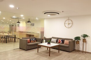 A modern living room with a sofa, coffee table, and potted plants. - Ginger Ahmedabad Rto Circle (Ahmedabad)