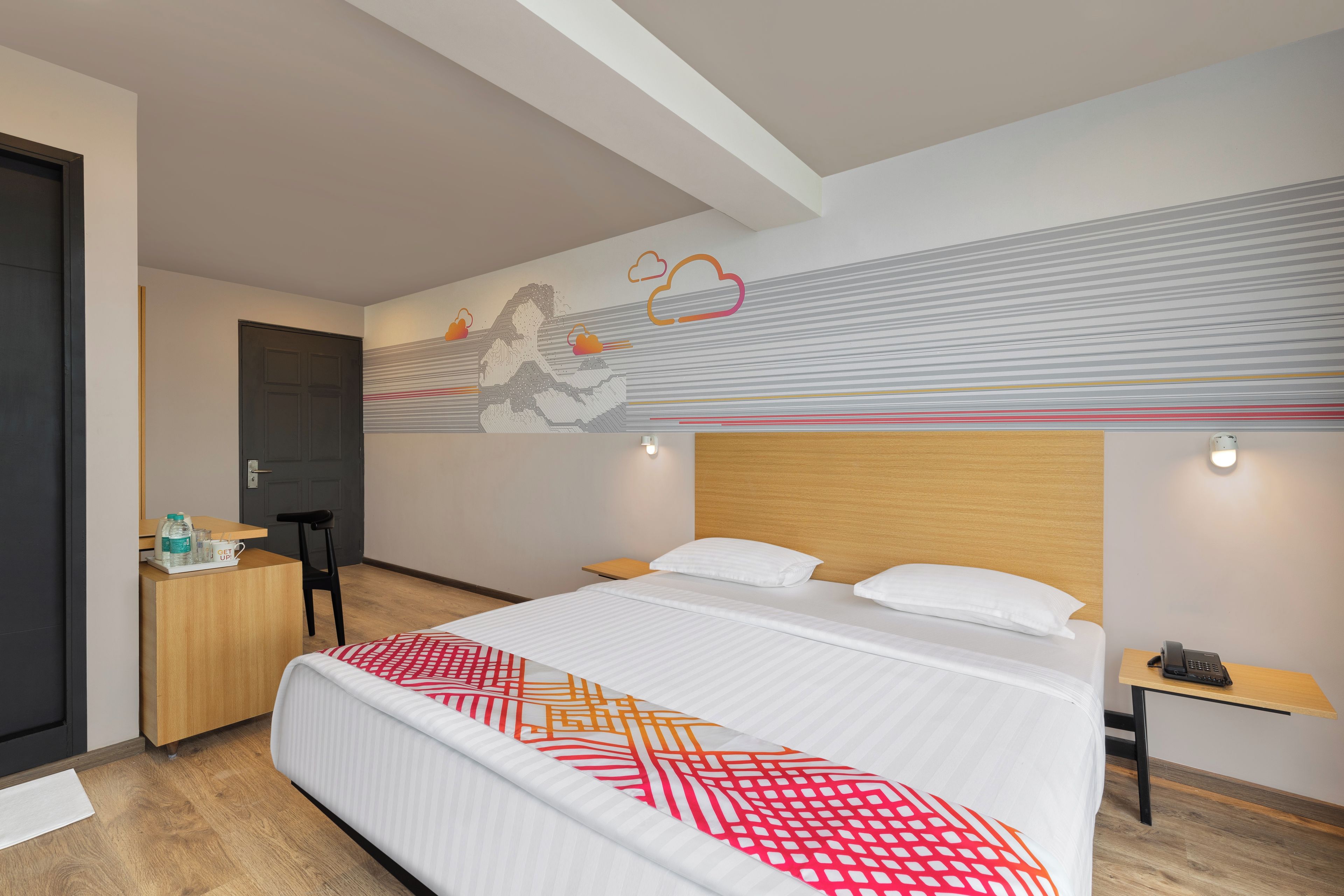 Een hotelkamer met een bed, nachtkastje en bureau met stoel.
