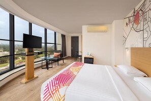 A modern hotel room with a large bed, a desk, and a TV.