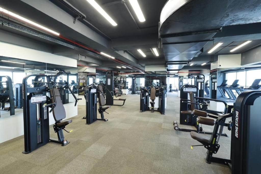 A gym with various exercise machines, mirrors, and treadmills.