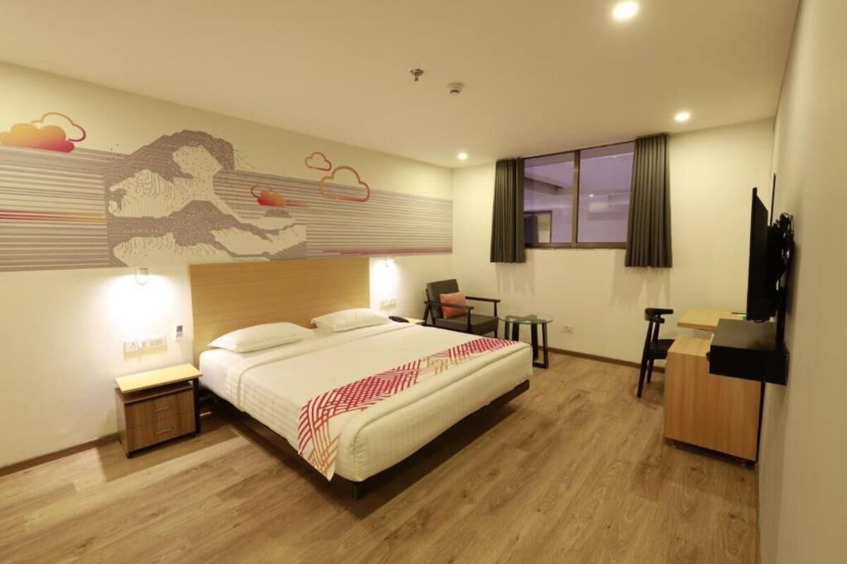 A hotel room with a bed, bedside tables, a desk, and a chair.