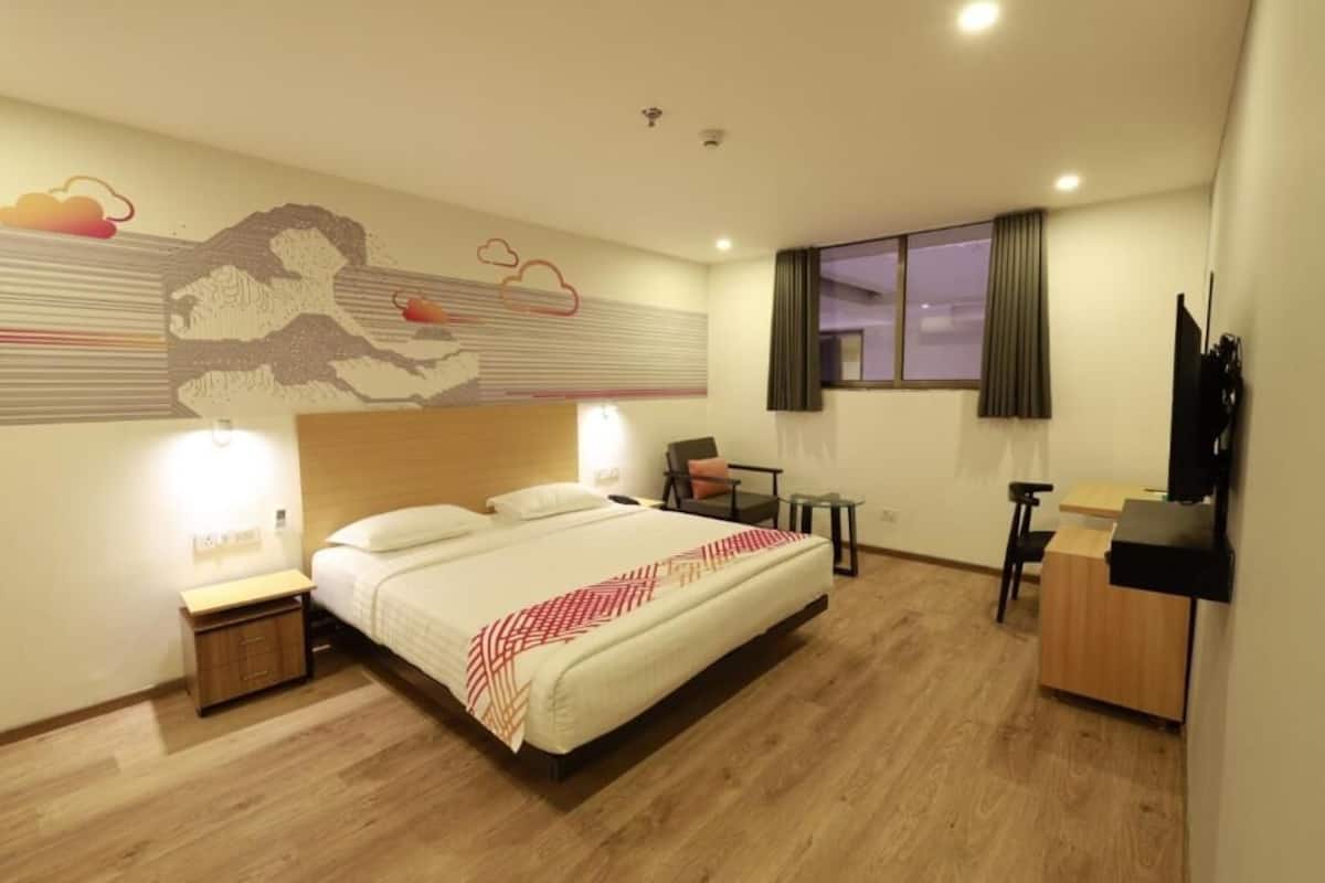 A hotel room with a bed, bedside tables, a desk, and a chair.