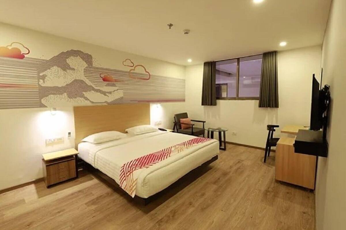 A hotel room with a large bed, a desk, a chair, and a TV.