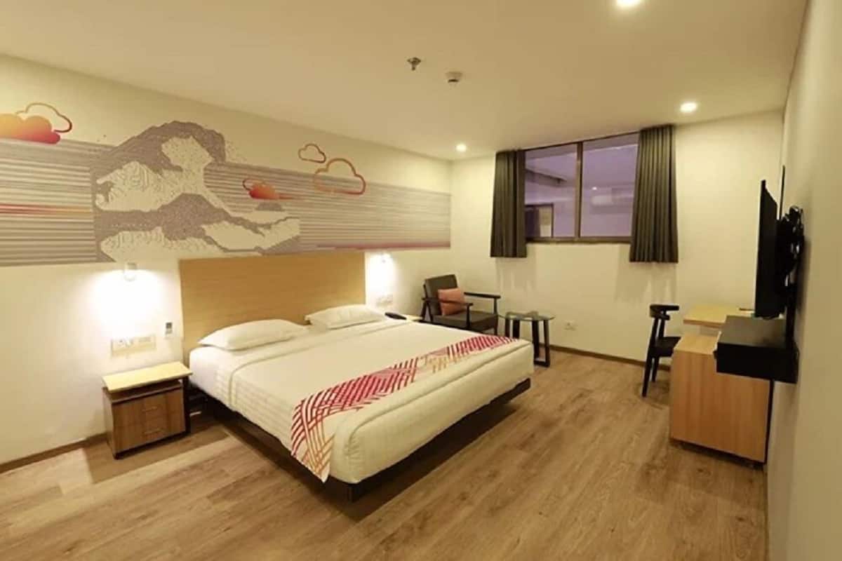 A hotel room with a large bed, a desk, a chair, and a TV.