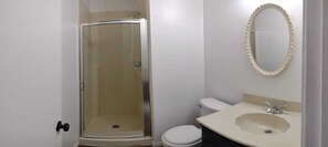 Features a compact bathroom with a glass-enclosed shower and a separate toilet.