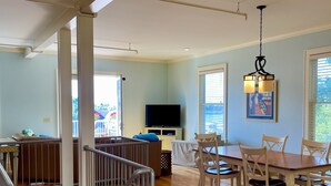 Un vaste espace de vie comprenant une table à manger, des chaises, un téléviseur et un escalier.