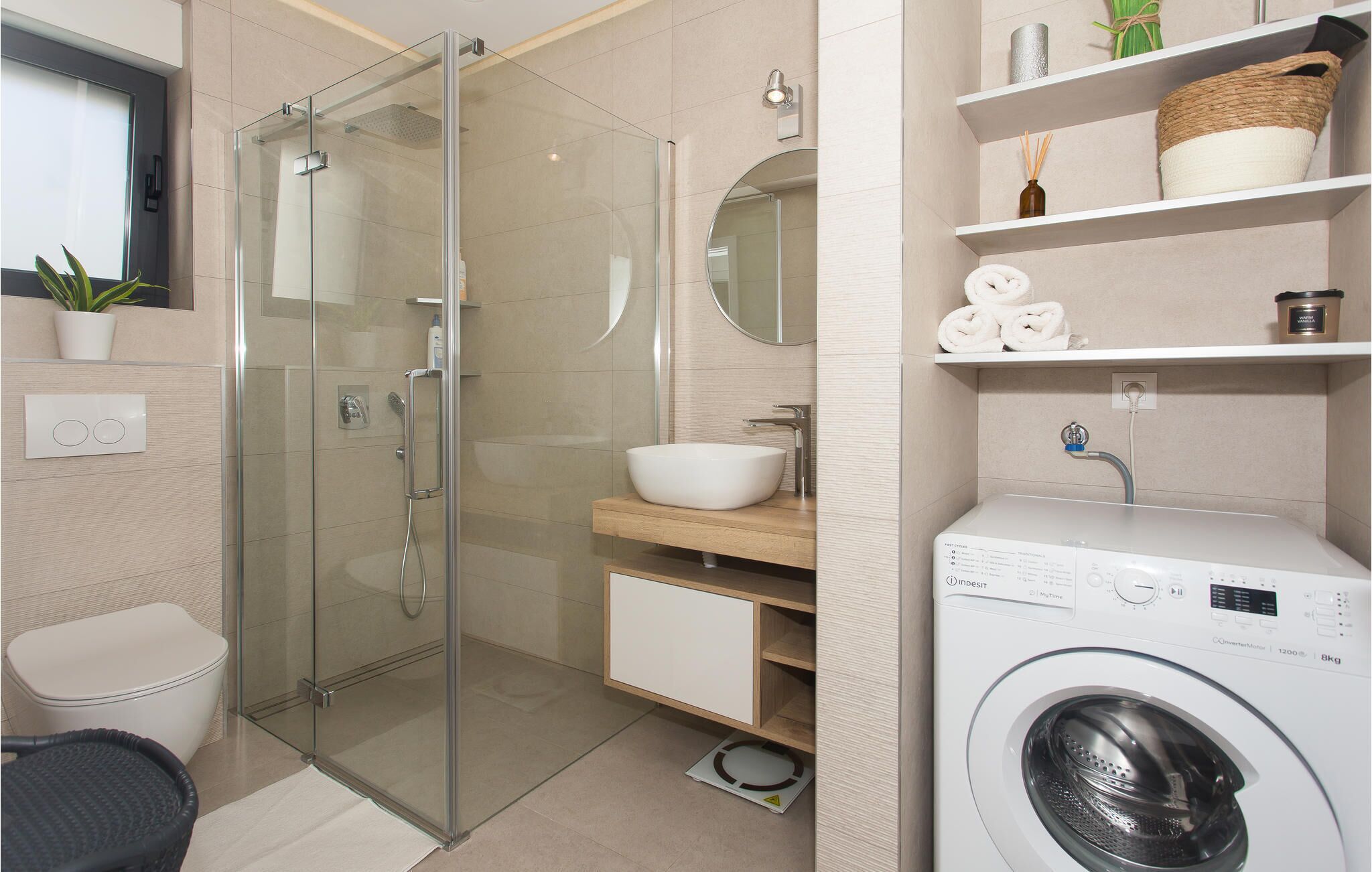 A modern bathroom with a glass-enclosed shower, a sink, and a built-in washing machine.