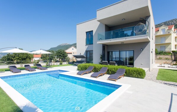 Un bâtiment moderne à deux étages doté d’une piscine, de chaises longues et offrant une vue sur les environs.