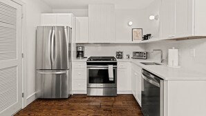 A modern kitchen with white cabinetry, stainless steel appliances, and a wooden floor. - Luxury 1BD Rittenhouse Sq. | Hosted By Stay Rafa (Philadelphia)