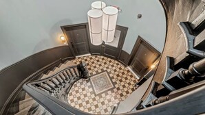 Un escalier en colimaçon avec un sol à carreaux et un luminaire moderne.