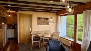A dining area with wooden furniture, a painting on the wall, and a view of greenery outside. - Orée du Bois OB D0 - CALM apartment 6 pers (Veysonnaz)