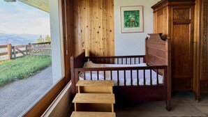 A wooden bed with a view of a mountain landscape, a framed picture on the wall, and a wooden cabinet.