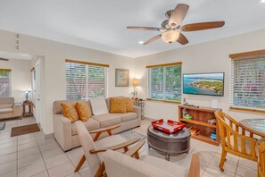 A living room with a sofa, chairs, a TV, and a ceiling fan.