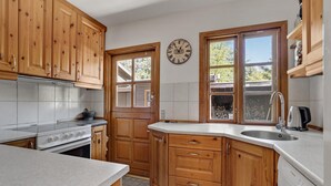 A kitchen with wooden cabinets, a stove, a sink, and a clock on the wall. - Awesome home in Højby with WiFi (Højby)